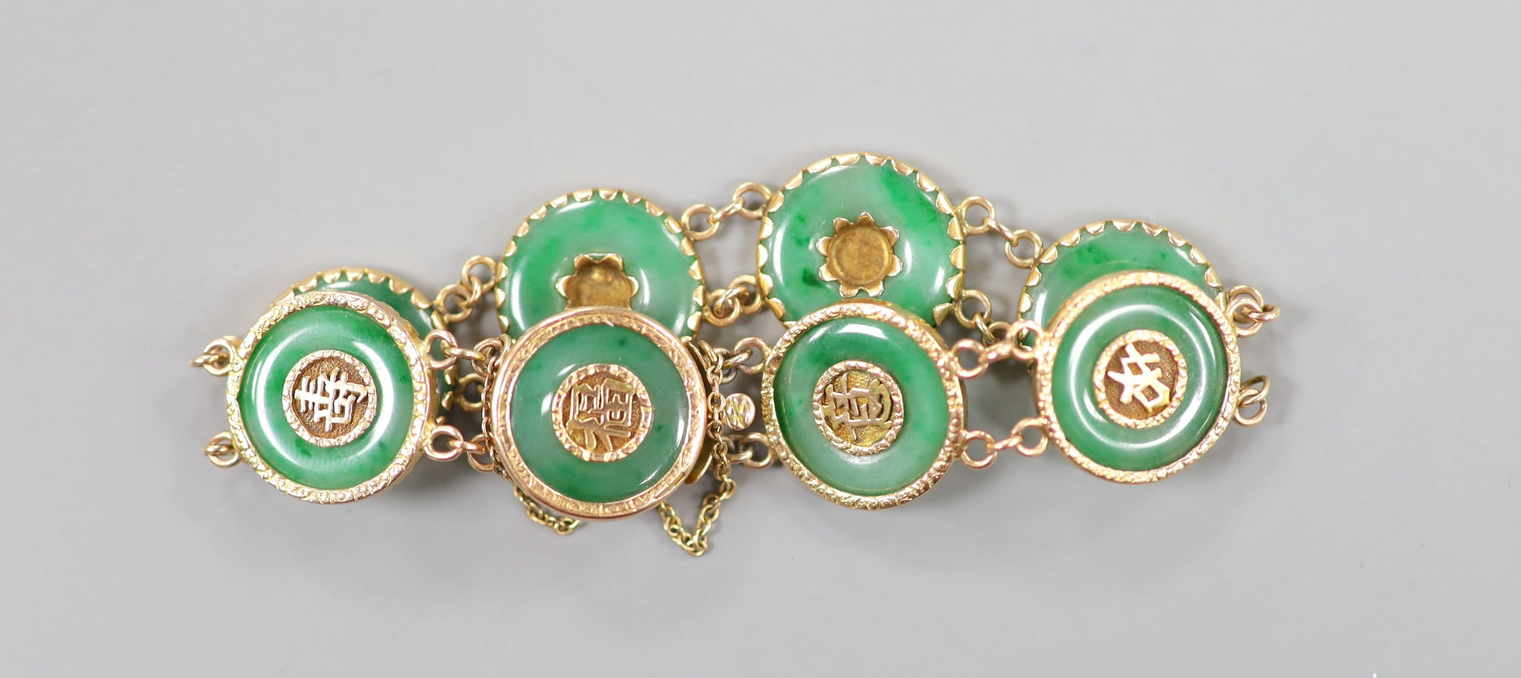 A Chinese yellow metal (stamped 18) and pierced eight stone jade disc set bracelet, with central Chinese characters, 16.5cm approx. gross weight 27.7 grams.